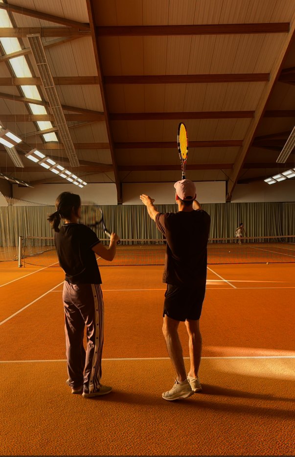 Coach guiding a student through the serve motion