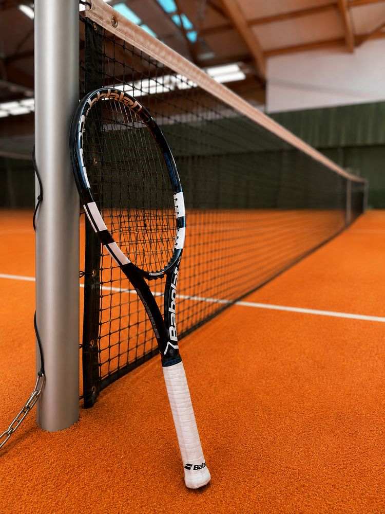 A racket resting against the net on the clay court