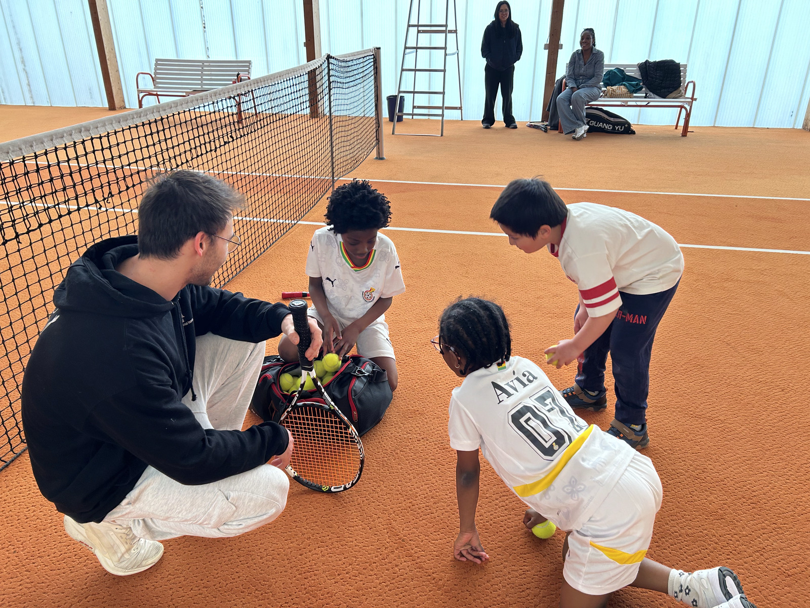 Coach Ido with junior players on an indoor clay court in Leipzig